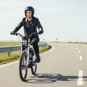 A person confidently riding a motorcycle that looks like a bicycle on a paved road, demonstrating its comfortable ergonomics and ease of handling.