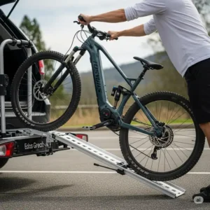 A close-up shot of a user rolling their electric mountain bike up a short, lightweight ramp, which is an integrated feature of the e bike rack with ramp.