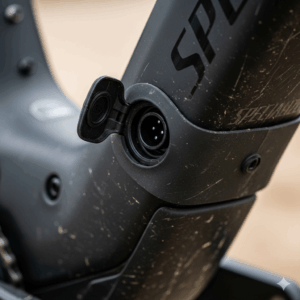  A close-up of the covered charging port on the frame of a Specialized Turbo Levo, showing it ready to be plugged in.